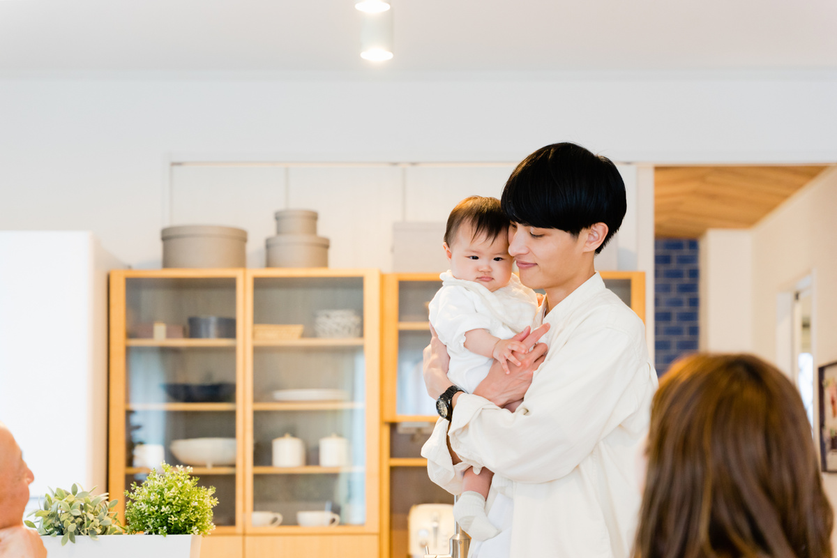 Father holding a baby at home and a family watching over