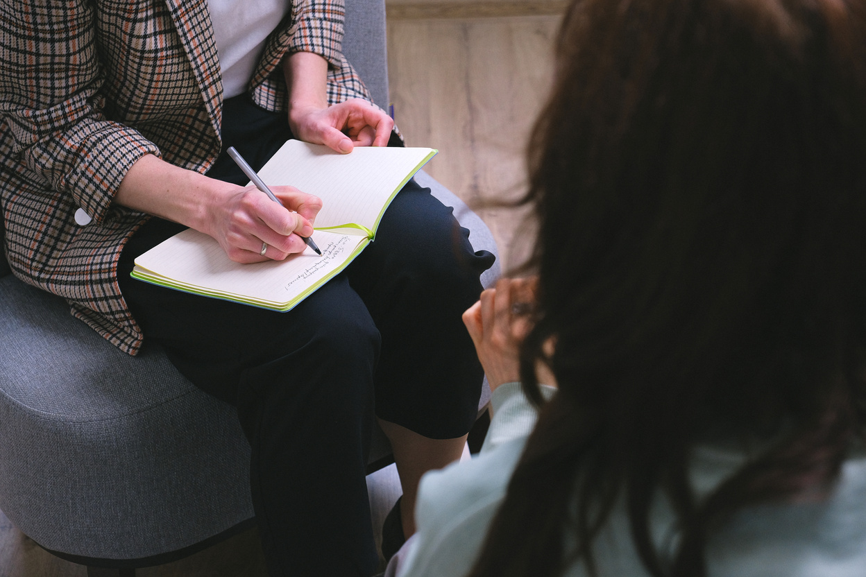 Crop counselor writing in diary while talking to patient